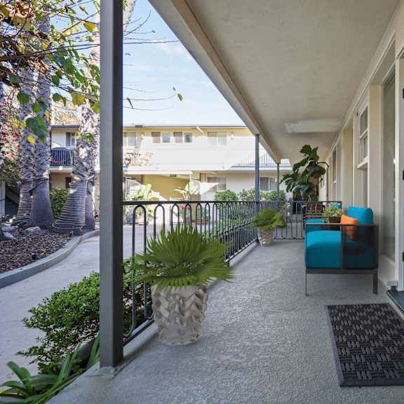 a patio with a blue couch and a pineapple planter.