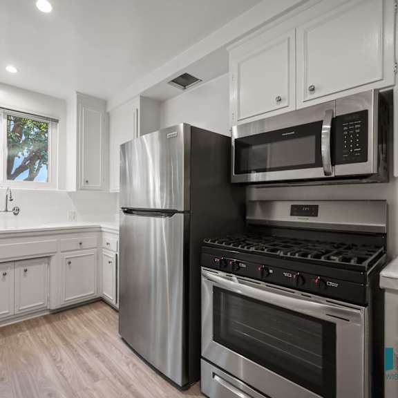 a modern kitchen with stainless steel appliances and white cabinetry.