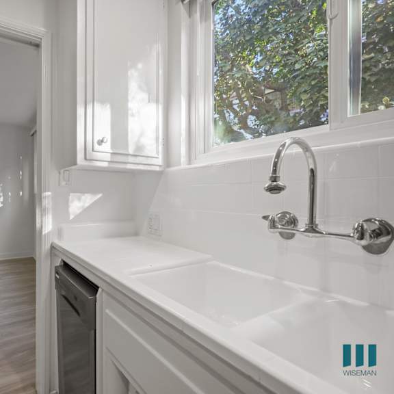 a white bathroom with a sink, mirror, and a fan.