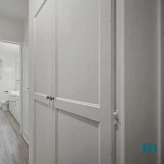 a hallway with white walls and wood flooring.