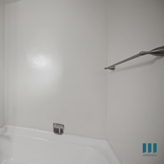 a white bathroom with a bathtub and a shower head.