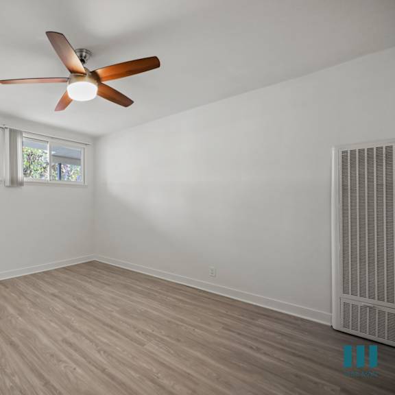 a room with a ceiling fan and wooden flooring.