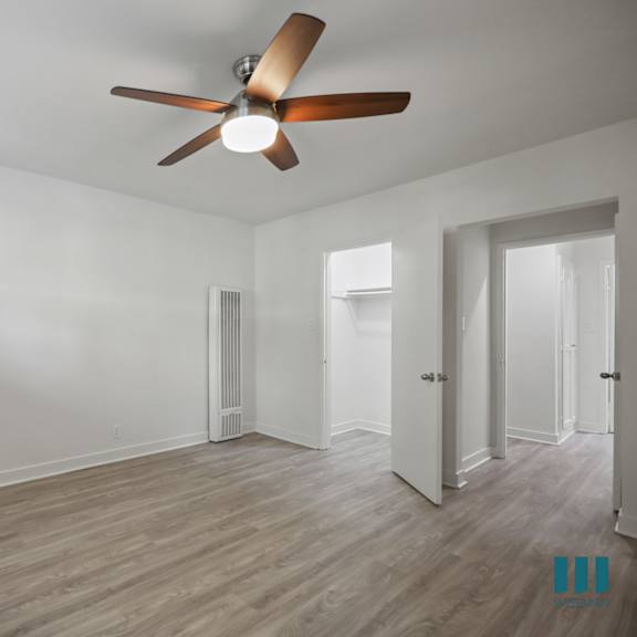 a room with a ceiling fan and wooden flooring.