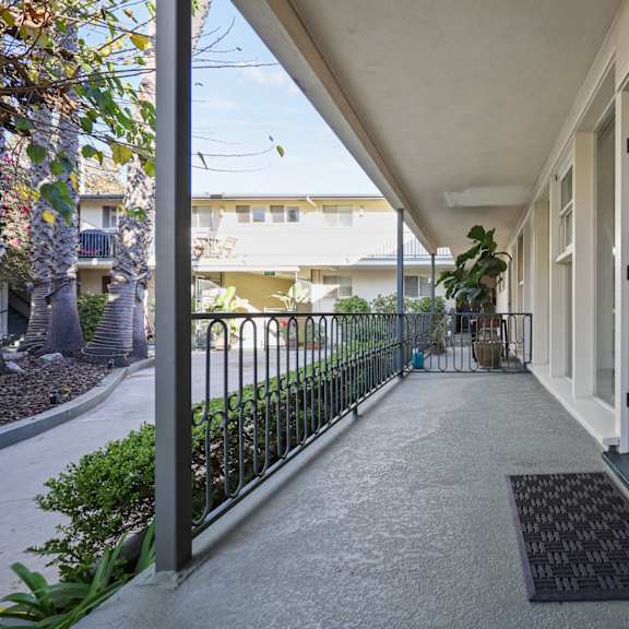 a black mat is on the concrete walkway of a building.