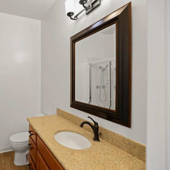bathroom with walk-in shower & glass door, and vanity cabinet storage