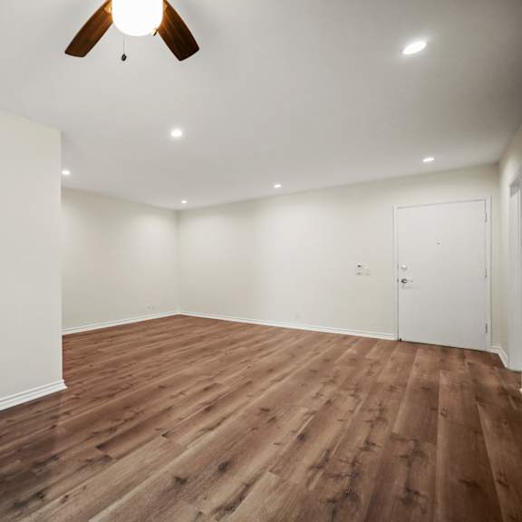 a living room with white walls and a ceiling fan