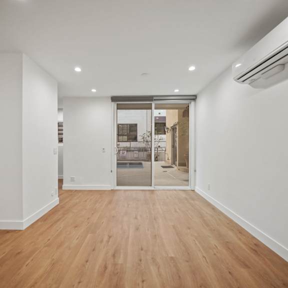 a living room with white walls and a sliding glass door