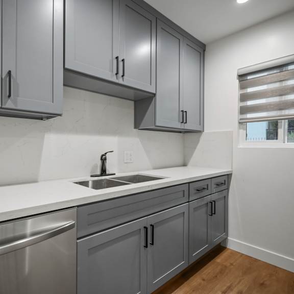 an empty kitchen with gray cabinets and stainless steel appliances