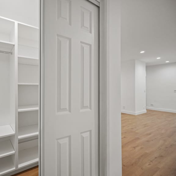 a walk in closet with white shelves and a white door