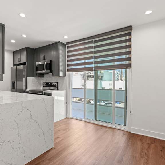 a kitchen with a marble island and a door to a balcony