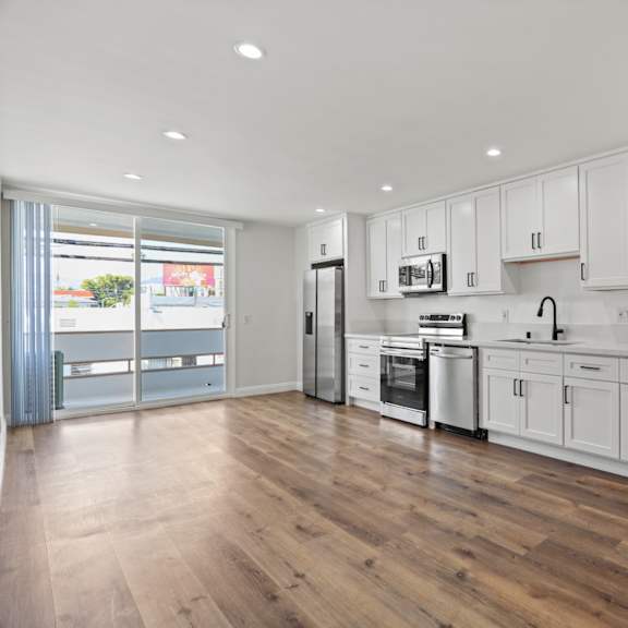a white kitchen with a washer and dryer and white cabinets