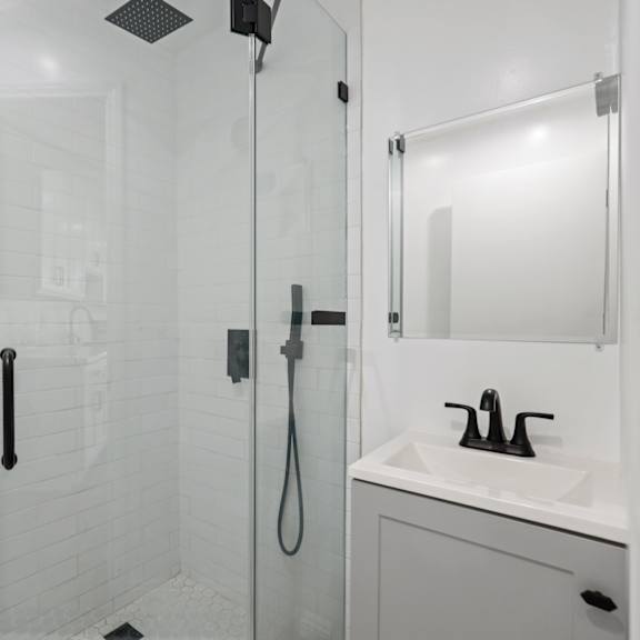 a white bathroom with a shower and a sink