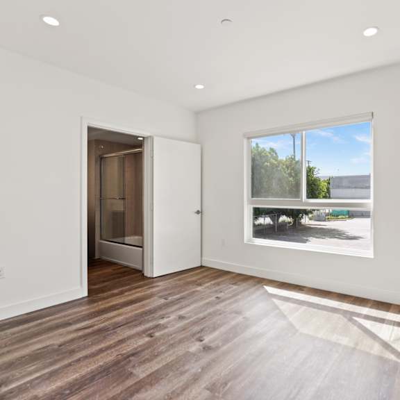bedroom with large windows, bathroom, and mirrored closet
