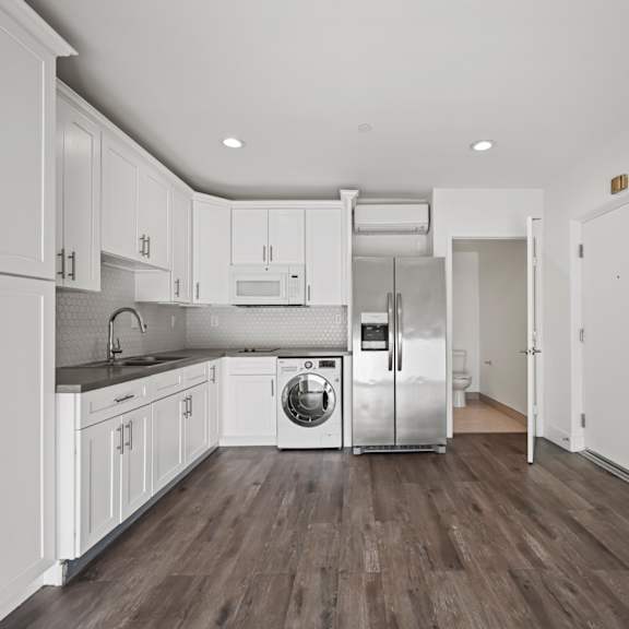 a kitchen with white cabinets and a washer and dryer in it.