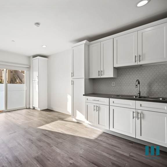a kitchen with white cabinets and a grey backsplash.