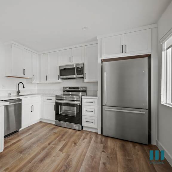 a modern kitchen with white cabinets and stainless steel appliances.