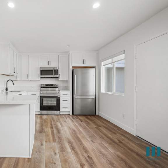 a kitchen with white cabinets and a wooden floor.