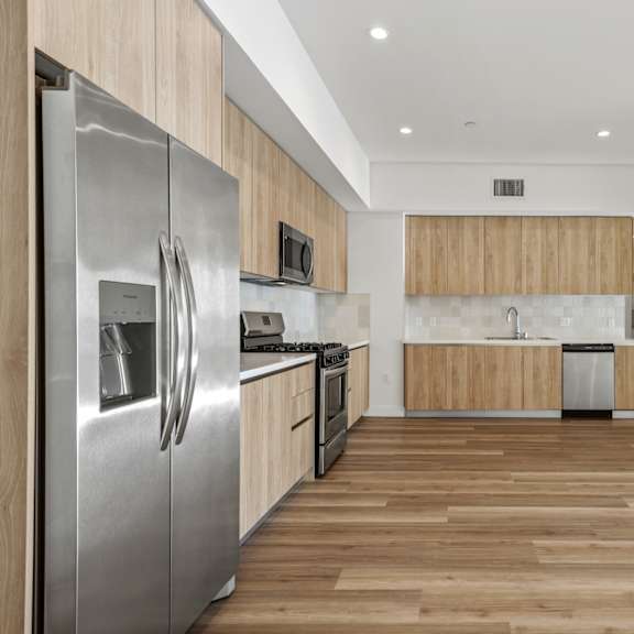 a modern kitchen with wooden cabinets and a stainless steel refrigerator.