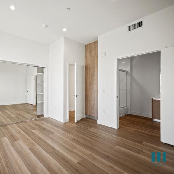 a spacious room with wooden flooring and white walls.