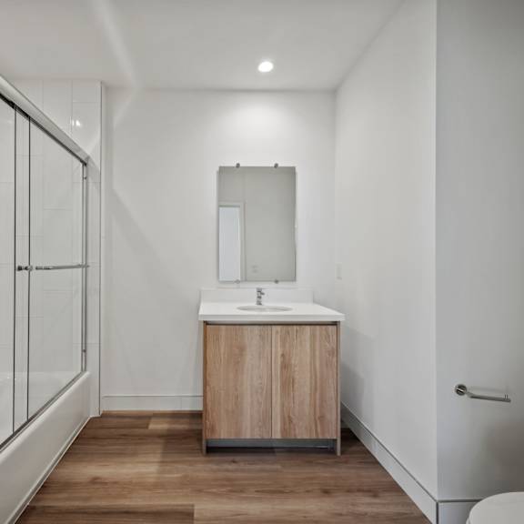 a modern bathroom with a wooden vanity and a walk-in shower.