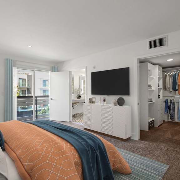 bedroom with walk-in closet with built-in organizers, bathroom, and balcony