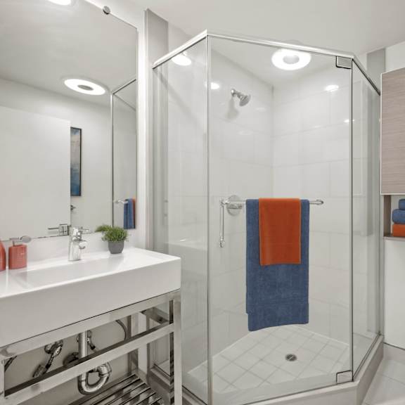 a bathroom with a white sink, a toilet, a shower with a glass door, and a mirror.