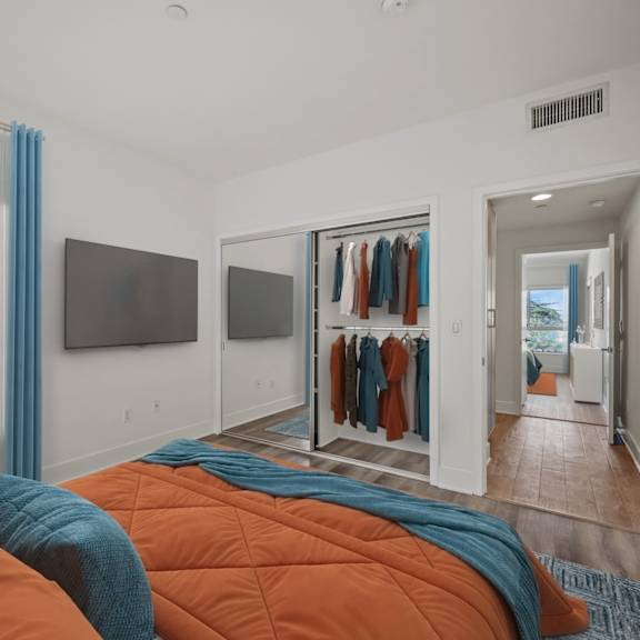 a bedroom with a bed covered in orange and blue comforters.