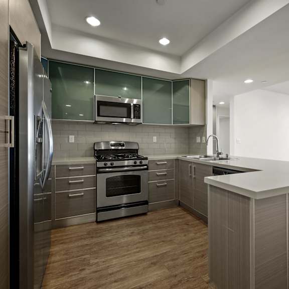 a modern kitchen with stainless steel appliances and wooden floors.