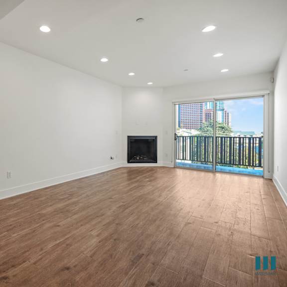 a spacious room with wooden flooring and a balcony with a railing.