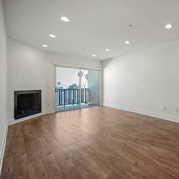 a spacious room with wooden flooring and a fireplace.