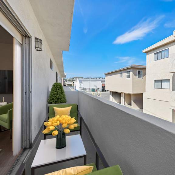 a balcony with a table and chairs overlooks a row of buildings.