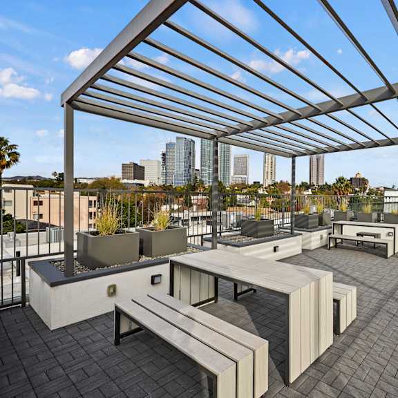 a rooftop patio with a metal pergola and benches.