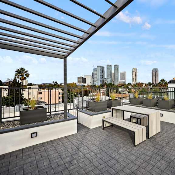 a rooftop patio with a bench and a table.