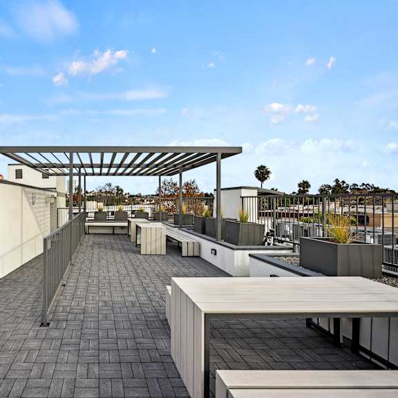 a rooftop patio with a long table and chairs under a canopy.