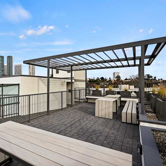 a rooftop patio with a bench and a metal pergola.