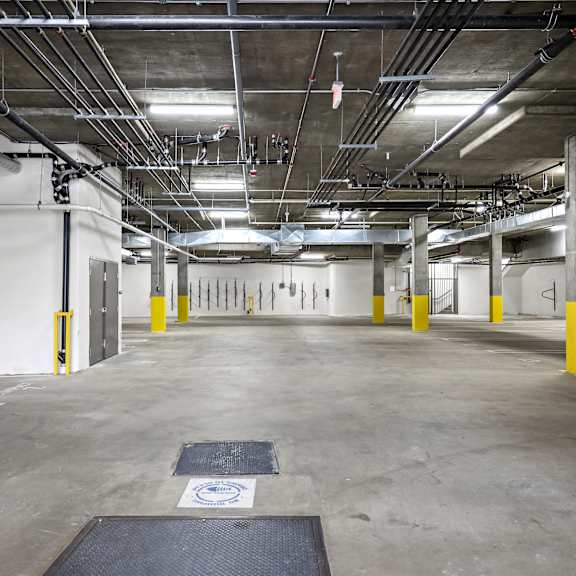 a large, empty parking garage with concrete floors and yellow bollards.