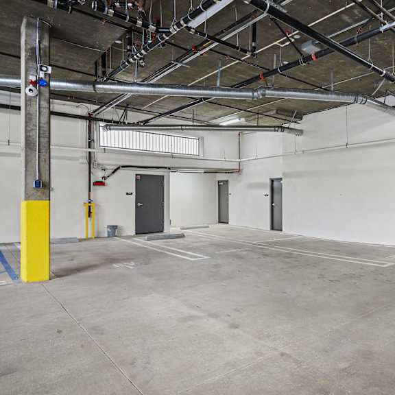 a large, empty parking garage with a concrete floor and yellow bollards.