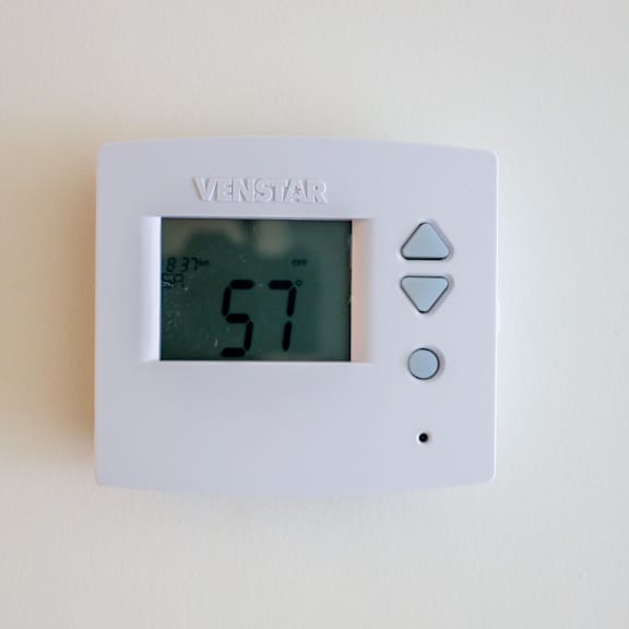 a white thermostat with the number 57 on the screen.