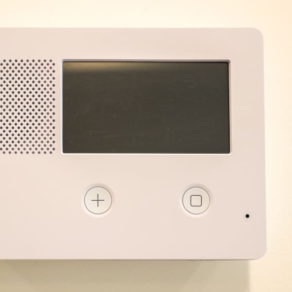 a white device with a black screen and a speaker on the left.