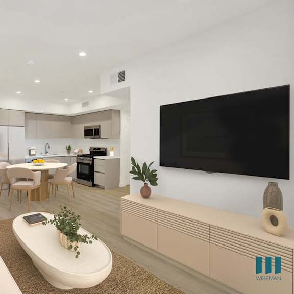 a modern living room with a white sofa, a coffee table, a flat screen tv, and a kitchen area in the background.