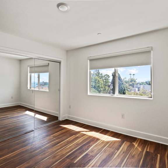 bedroom with vinyl flooring, mirrored closet, and vinyl flooring