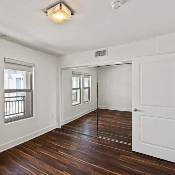 bedroom with mirrored closet, vinyl flooring, and double windows