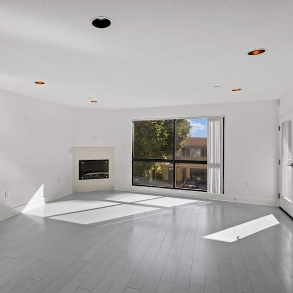 large-size living room with electric fireplace, patio, and windows