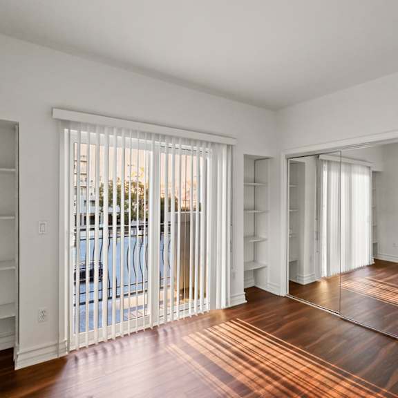 bedroom with mirrored closet, built-in shelving, and balcony