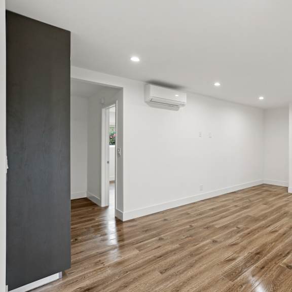 large bedroom with wall heater, cabinet storage, and window shades