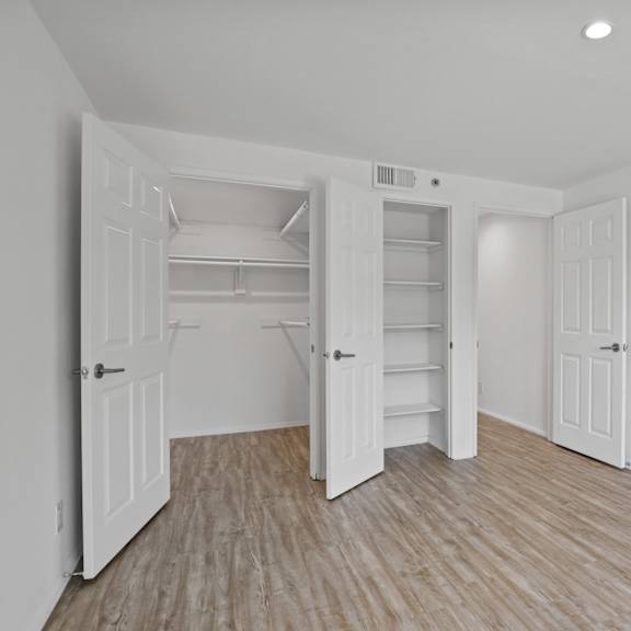 west la apartment bedroom with closet, built-in shelving, and vinyl flooring