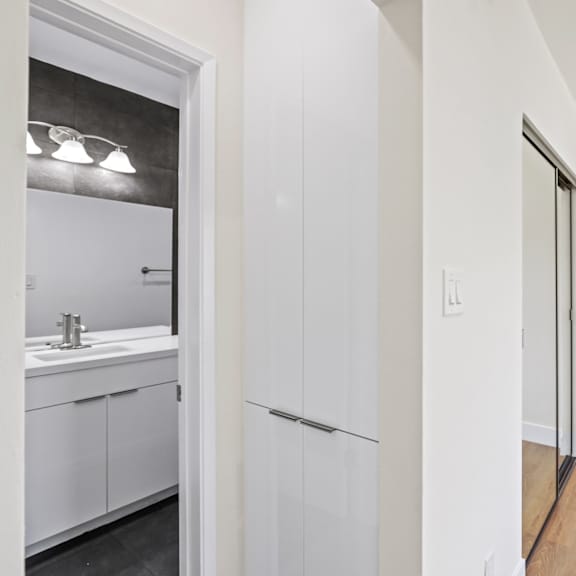bedroom with built-in cabinet storage, mirrored closet, and bathroom