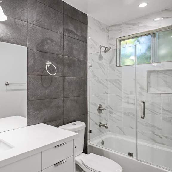 bathroom with shower bath with glass door and vanity cabinet storage