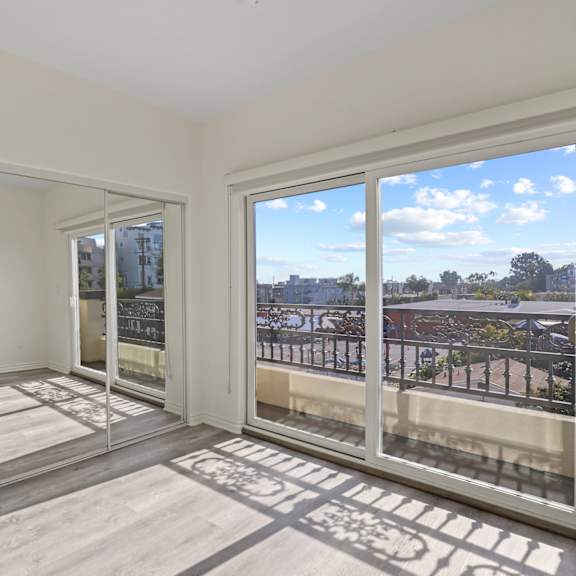 bedroom with mirrored closet, private balcony, and vinyl flooring
