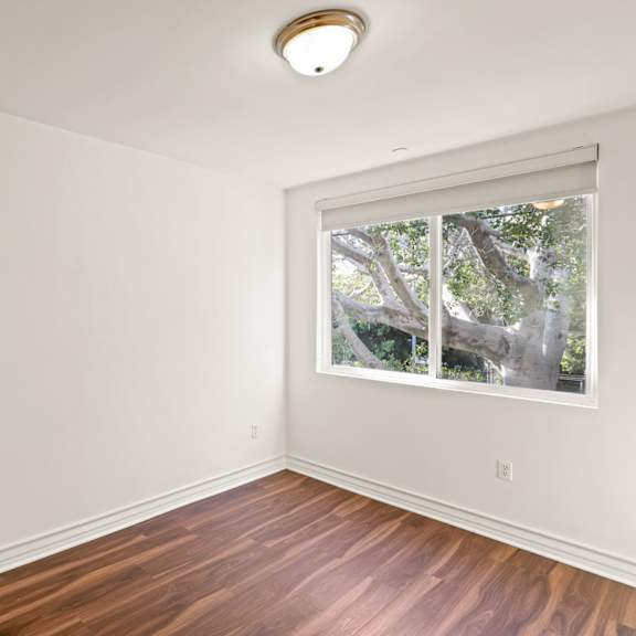 bedroom with mirrored closet, large window, and vinyl flooring